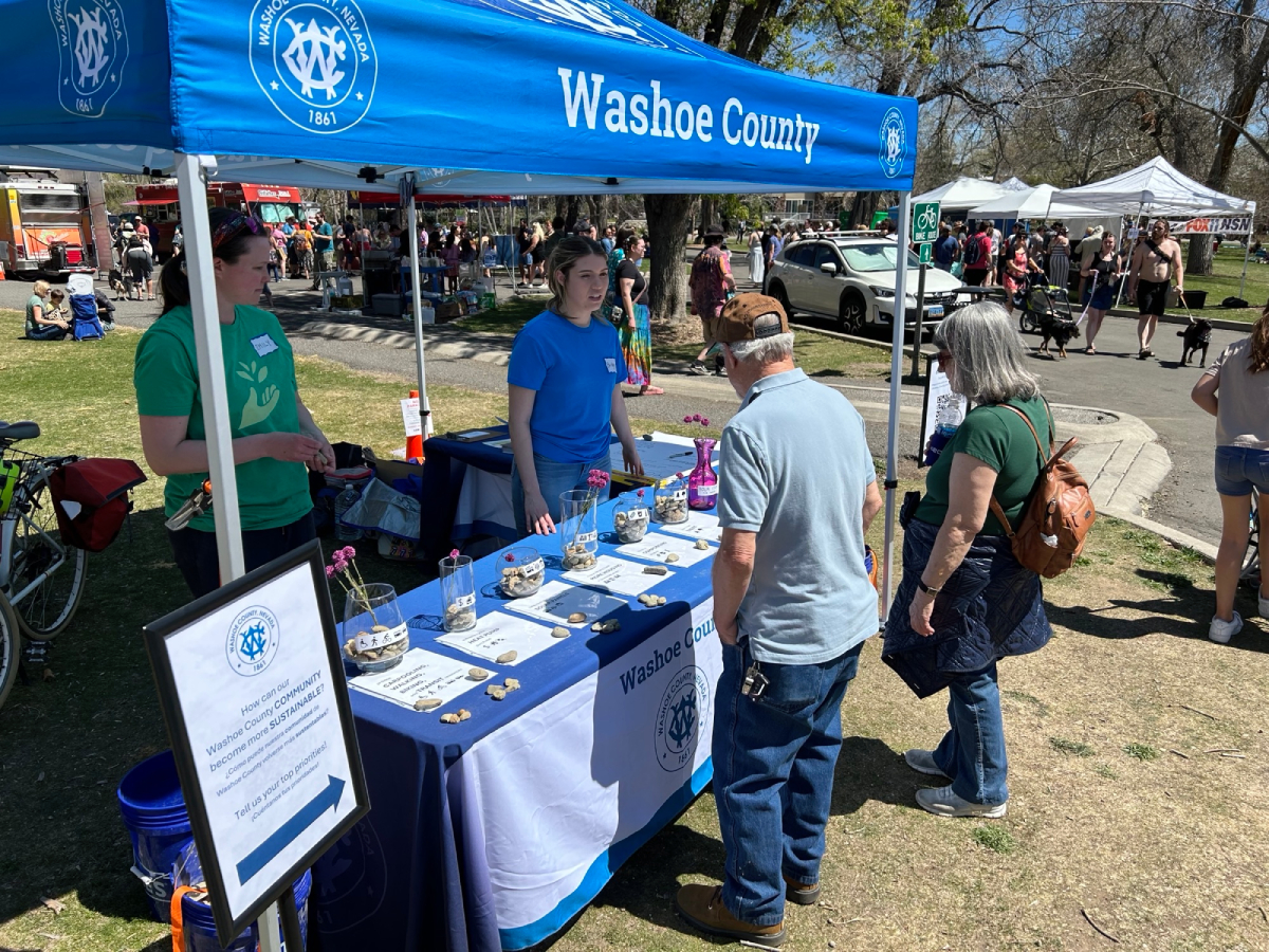 Two people chat with two staff members at the Washoe County tent at Earth Day